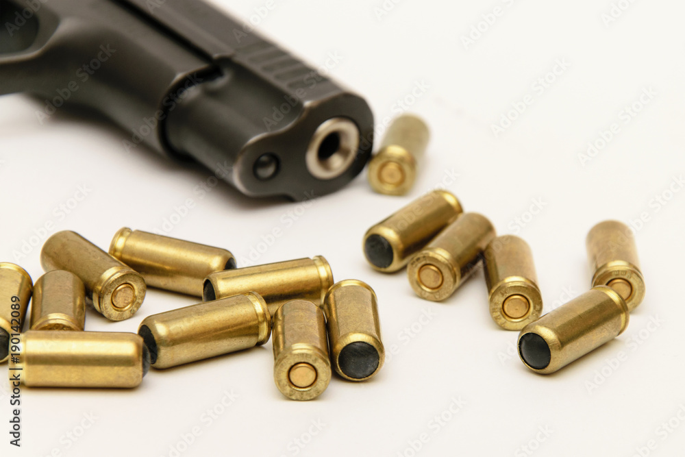 A gun barrel and golden bullets on a light background close-up