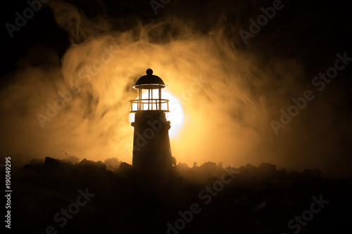 Lighthouse with light beam at night with fog.