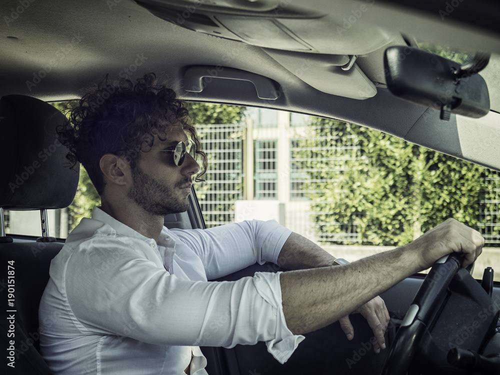 Handsome Man Behind the Wheel Driving a Car, wearing white shirt, hand on wheel