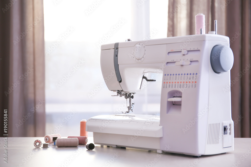 Modern sewing machine with threads on table