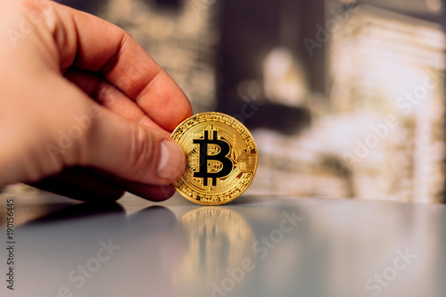 golden bitcoin on a table in a man's hand
