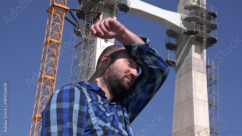 Overworked exhausted tired engineer builder wiping sweat construction industry