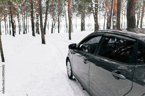 a silvery car in a snowy winter forest road