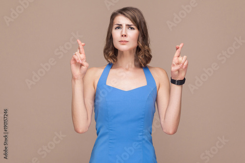 Hope, wish concept. Well dressed woman crossed fingers and looking at camera photo