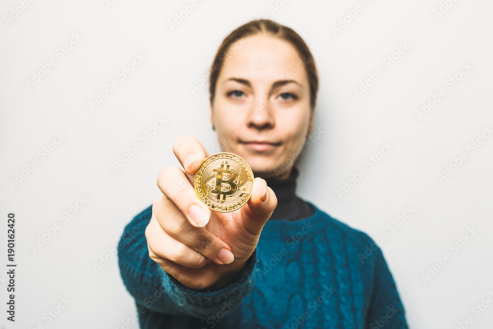 Young woman shows Golden Bitcoin coin - symbol of cryptocurrency, new virtual money, selective focus Young woman shows Golden Bitcoin coin - symbol of cryptocurrency, new virtual money, selective focus