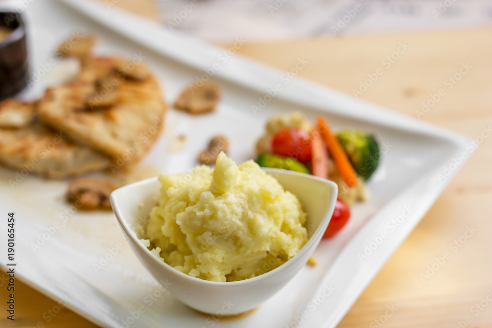Grilled chicken steak with small mushroom and muchroom sauce in the white dish in the natural light in restaurant. Grilled chicken steak with small mushroom and muchroom sauce in the white dish in the natural light in restaurant.