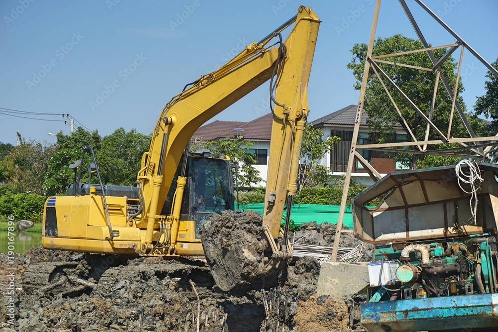 Makro excavator working to adjust surface for construction site. labour control makro truck to remove soil and dirt. construction concept Makro excavator working to adjust surface for construction site. labour control makro truck to remove soil and dirt. construction concept