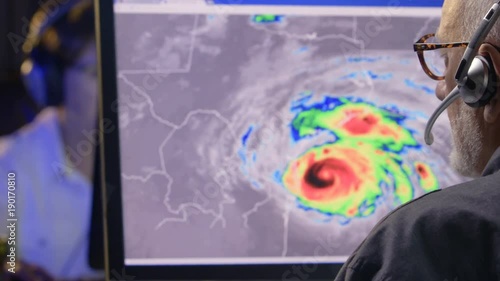 Weather professional monitoring hurricane activity on computer screen