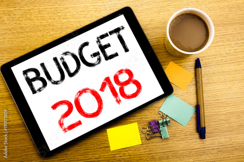Handwritten text caption showing Budget 2018. Business concept writing for Household budgeting accounting planning Written on tablet laptop, wooden background with sticky note, coffee and pen