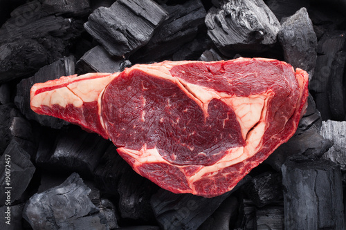 Raw fresh meat Ribeye steak on black charcoal background photo