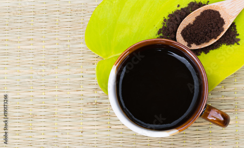 Coffee lover.Coffee cup on green leaf with roasted coffee on wooden spoon.Background with copy space.