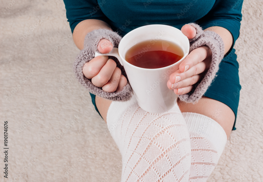 White cup with tea in the hands of a girl White cup with tea in the hands of a girl