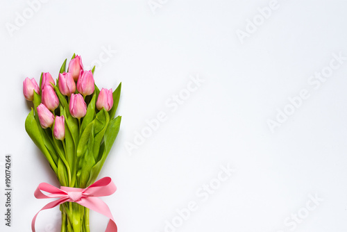 Obraz na płótnie Top view of pink tulips bouquet, wrapped with pink ribbon over white background. Copy space. w salonie