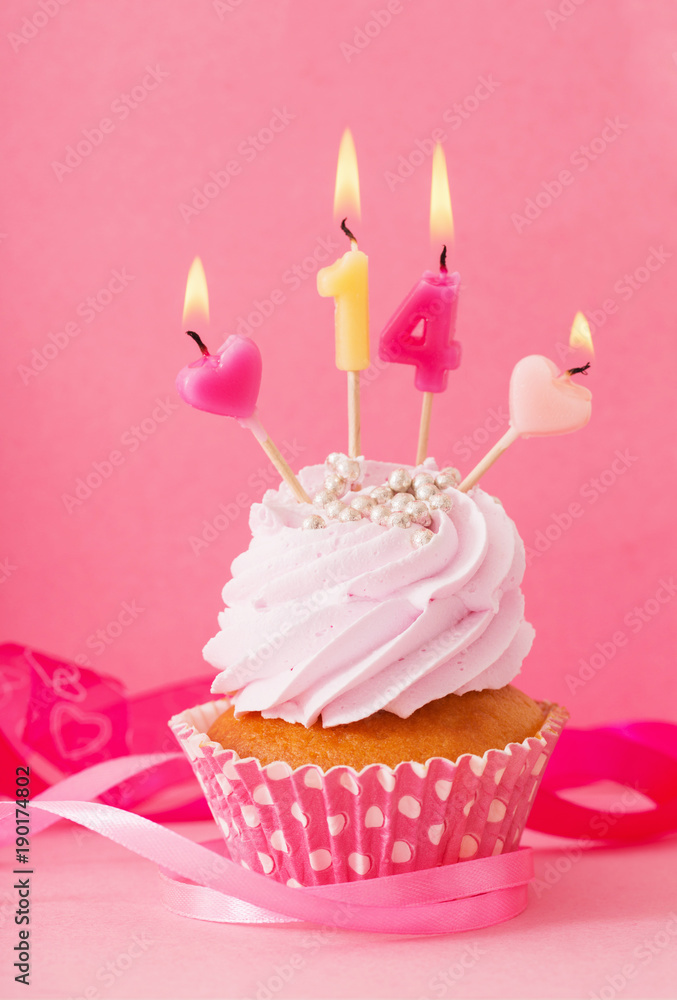 cupcake with candle on pink background