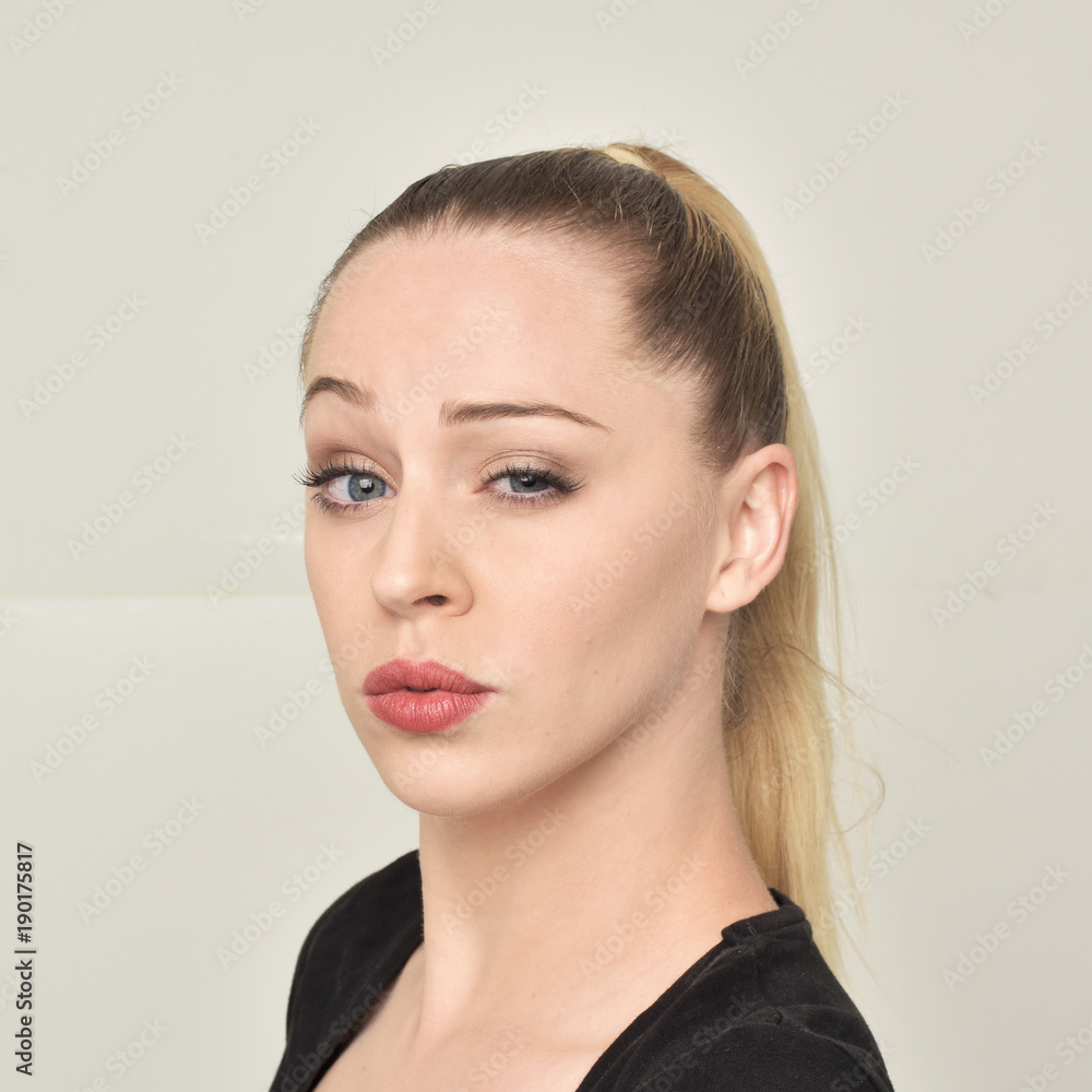 Fototapeta premium close up portrait of pretty blonde girl pulling different facial expressions. soft studio background.