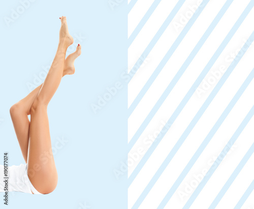 Woman's legs with smooth skin after depilation on pastel blue background.
