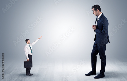 Small businessman pointing to a giant businessman
