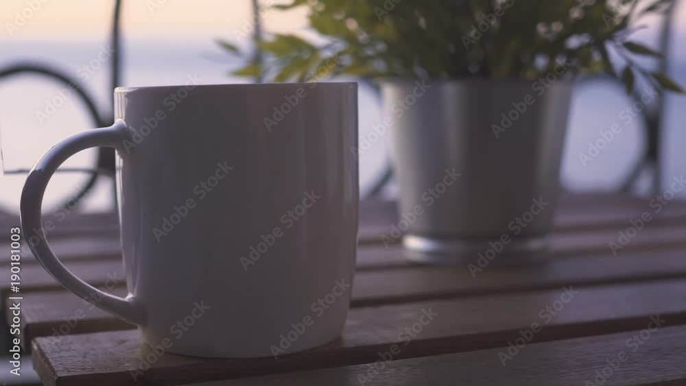 Young man takes cup of coffee near sea at sunny morning Young man takes cup of coffee near sea at sunny morning