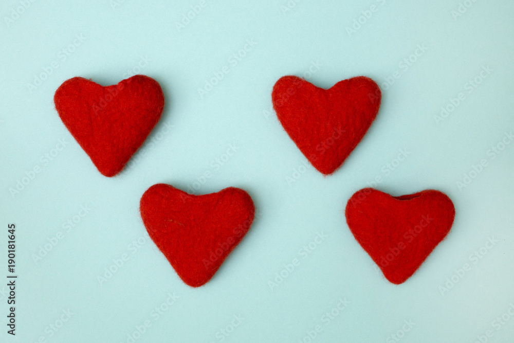 Four valentines made of felted wool in the form of hearts on a green background