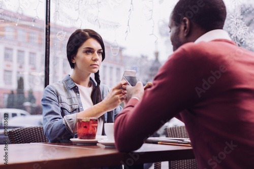 Huge offense. Upset sad nice woman sitting while gazing straight and carrying phone