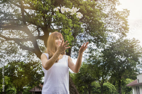 Beautiful young asian woman throw a white flowers up in the air over her head