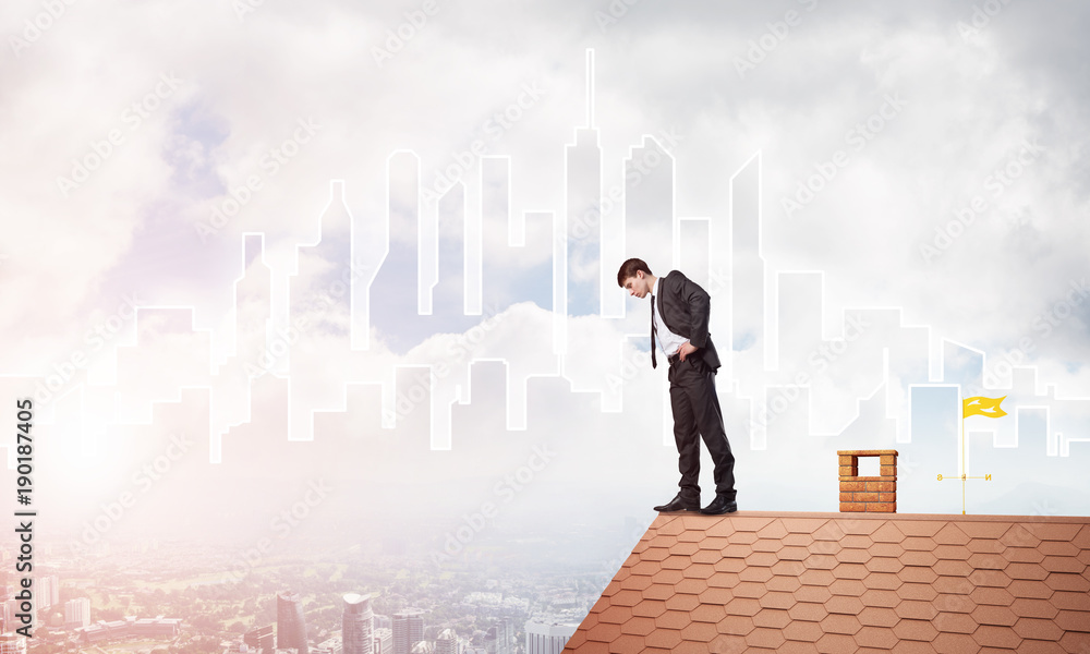 Businessman looking down from roof and modern cityscape at background. Mixed media Businessman looking down from roof and modern cityscape at background. Mixed media