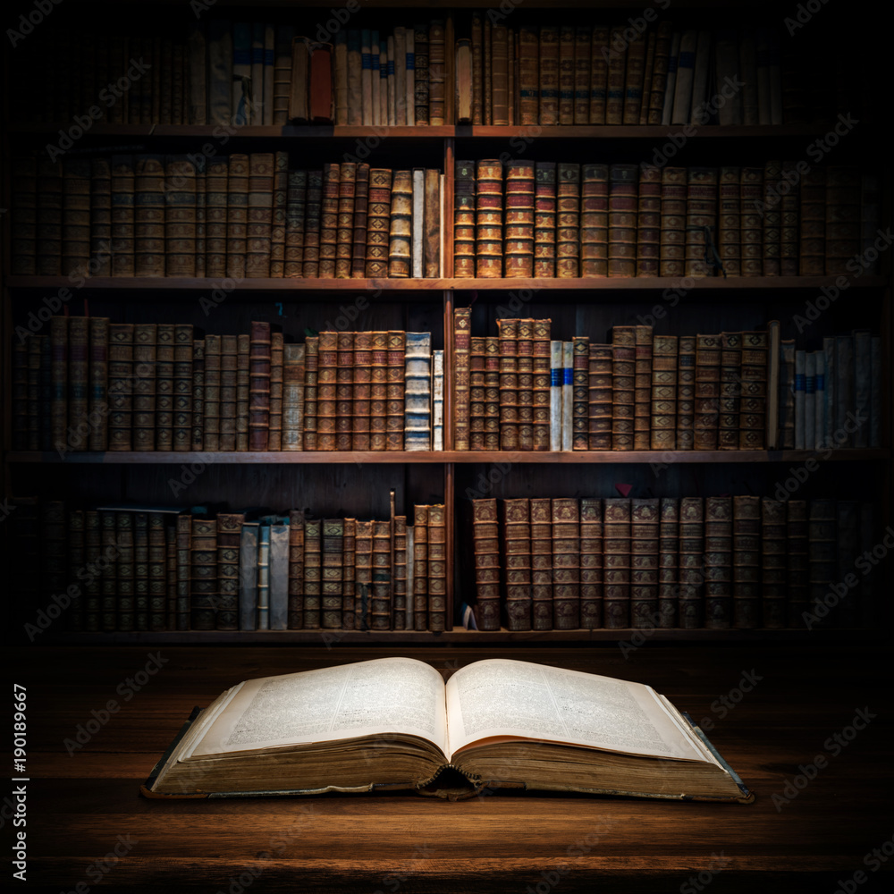 Obraz premium Open old book on a bookshelf background. Selective focus.