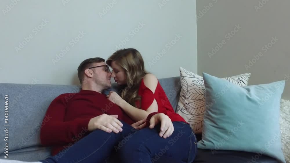Pan up past rose petals to cute couple kissing on a couch Pan up past rose petals to cute couple kissing on a couch