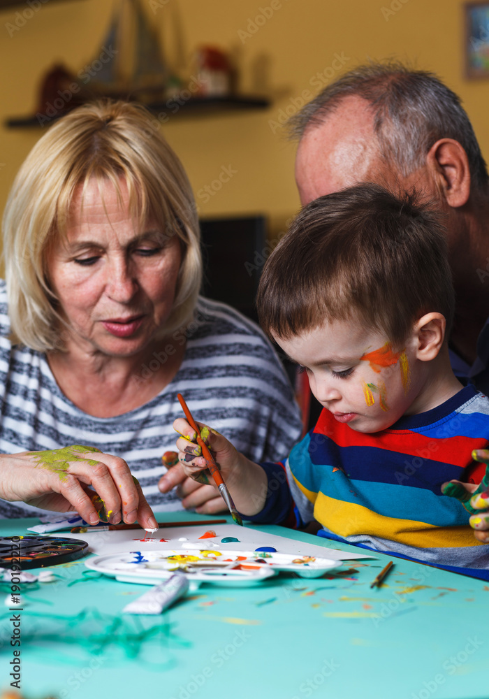 Grandmother and grandfather with grandson drawing together at home. Grandmother and grandfather with grandson drawing together at home.