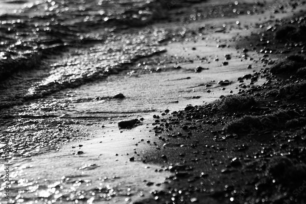 A close view of water on a lake shore, with details of sands and little round stones A close view of water on a lake shore, with details of sands and little round stones