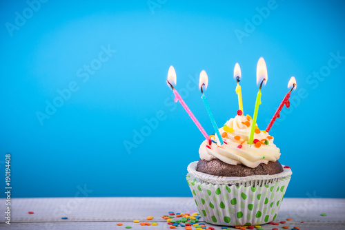 Birthday cupcake on a color background with multicolor candles photo