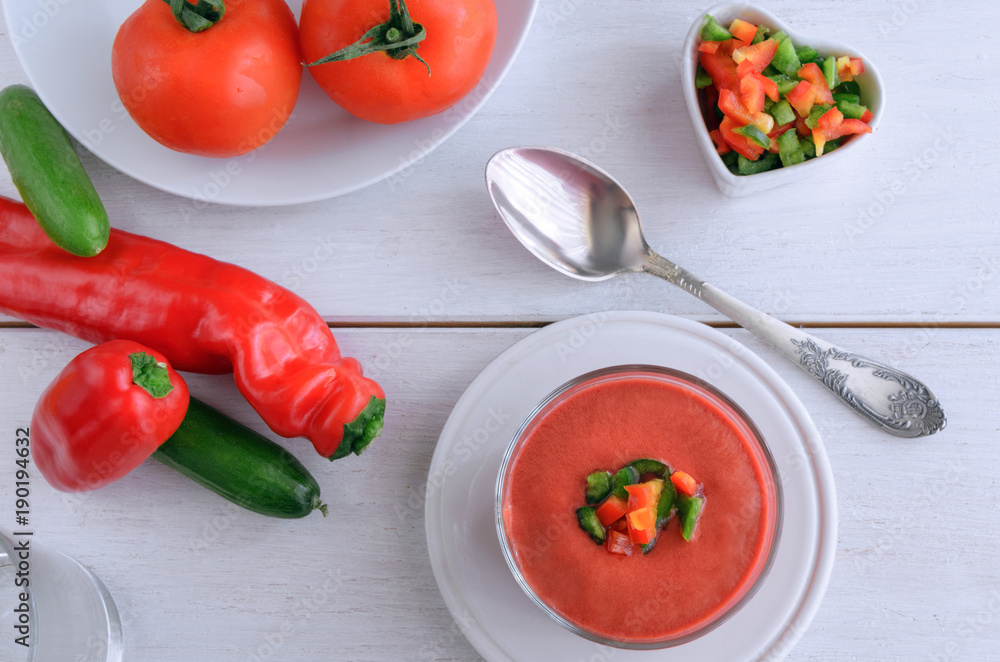 Gazpacho, tomato soup made from made of raw blended vegetables. Traditional Spanish cold soup in glass bowl on wooden table.Top view Gazpacho, tomato soup made from made of raw blended vegetables. Traditional Spanish cold soup in glass bowl on wooden table.Top view