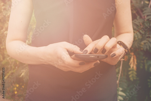 The girl's hand with the black smartphone. Close up.
