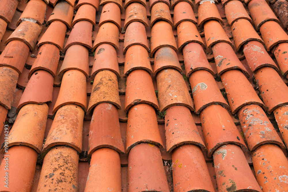 Close-up of red shingles shabby from the weather on the roof of house. Background image. Conceptual wallpaper Close-up of red shingles shabby from the weather on the roof of house. Background image. Conceptual wallpaper