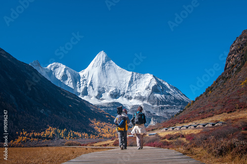 Male and female traveller at Yading Nature Reserve, Daocheng county, Ganzi Tibetan Autonomous Prefecture, Sichuan province of China. The holy peak Yangmaiyong (Jampelyang) can been seen in the backgro photo