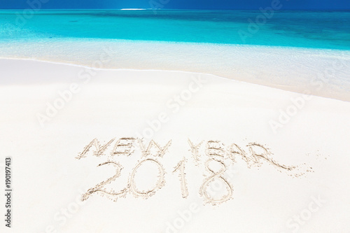 Inscription word NEW YEAR and numbers 2018 on sandy beach