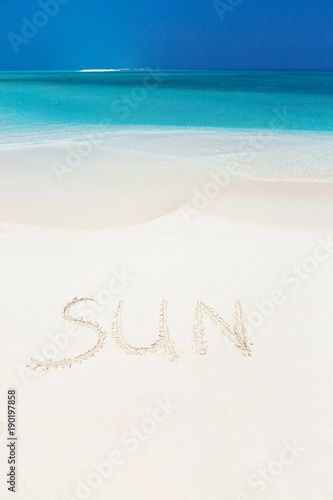 Handwritting inscription word SUN on sandy beach