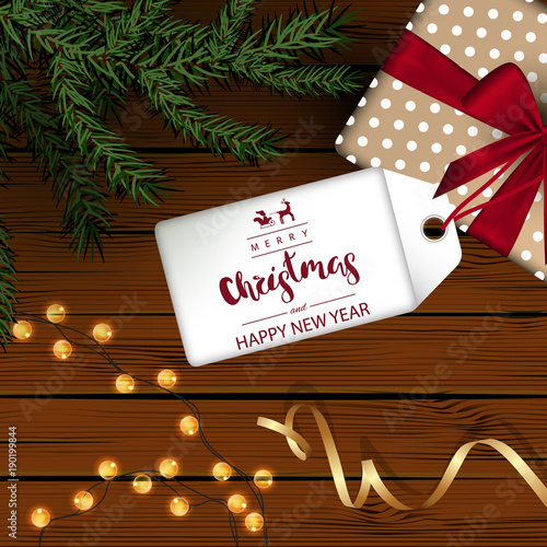 Template square holiday background. Wooden boards. Green branches and a garland, a gift with a red bow, a gold ribbon. Inscription Lettering "Happy New Year and Merry Christmas"  white tag. Vector.