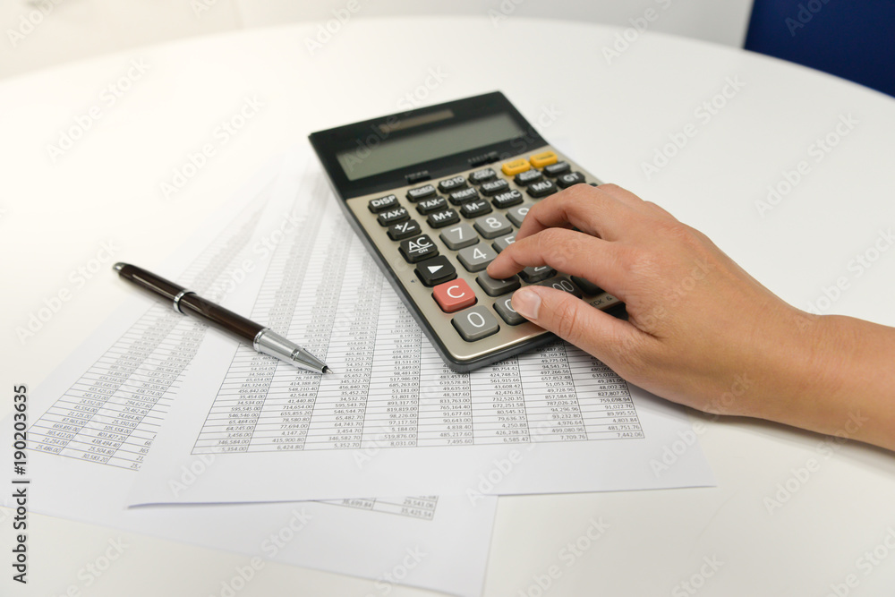Woman hand is using the calculater to calculate the finance document Woman hand is using the calculater to calculate the finance document