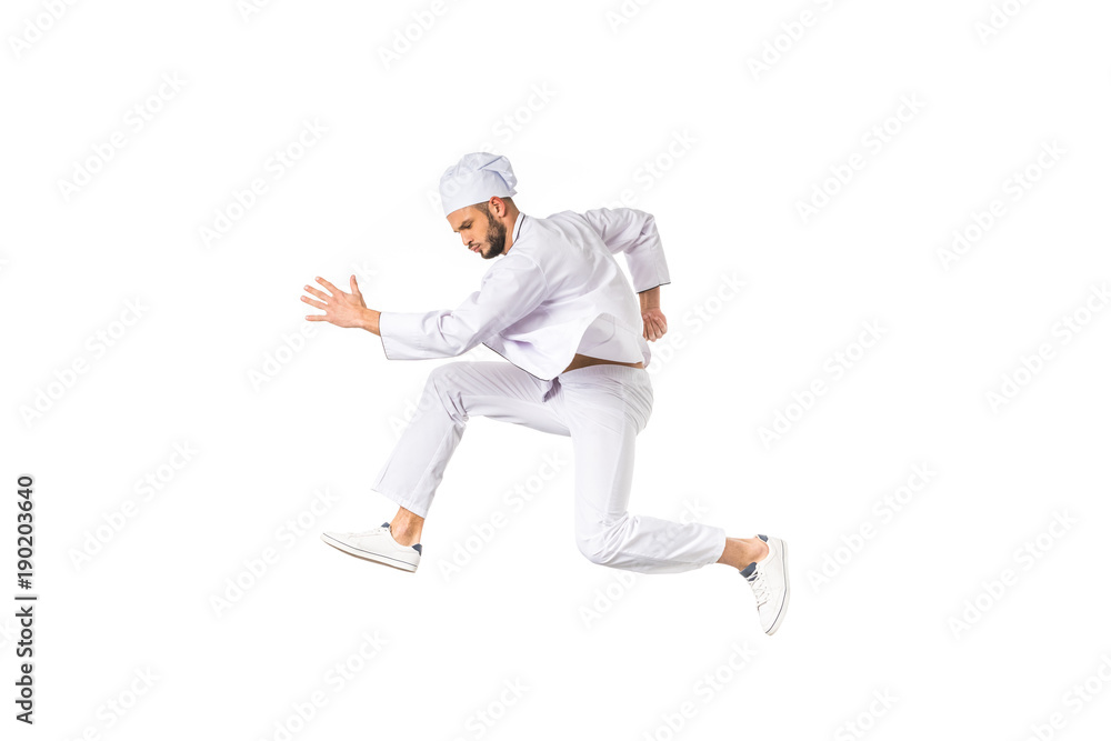 side view of young chef running and jumping isolated on white