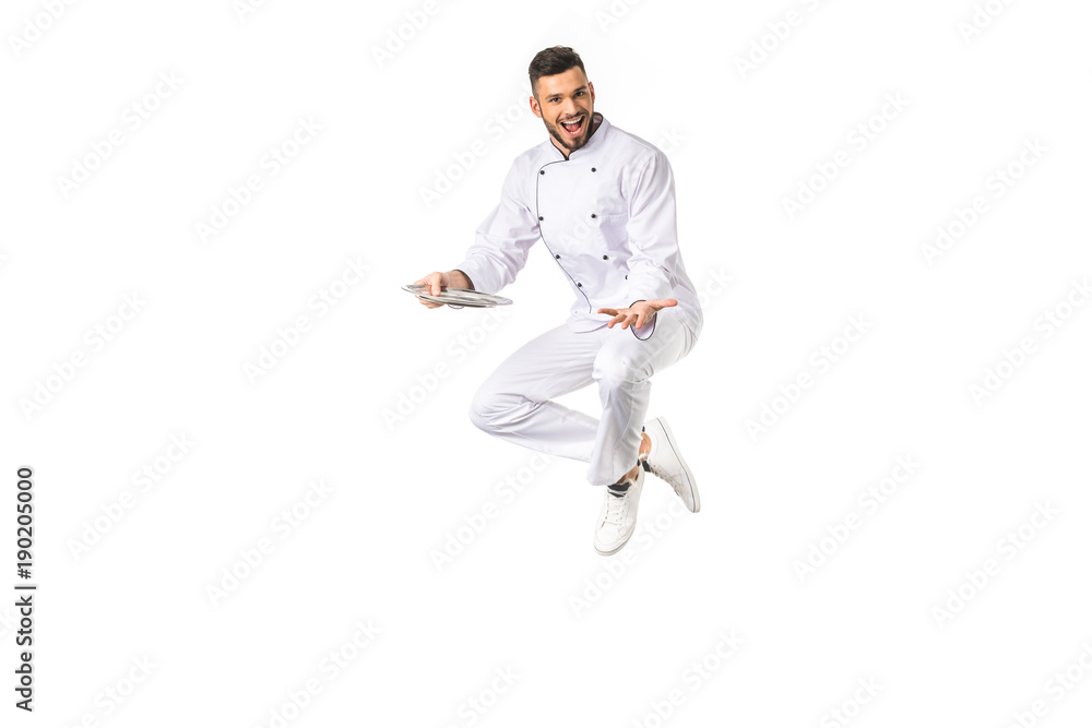 happy young male chef with plate jumping and smiling at camera isolated on white happy young male chef with plate jumping and smiling at camera isolated on white