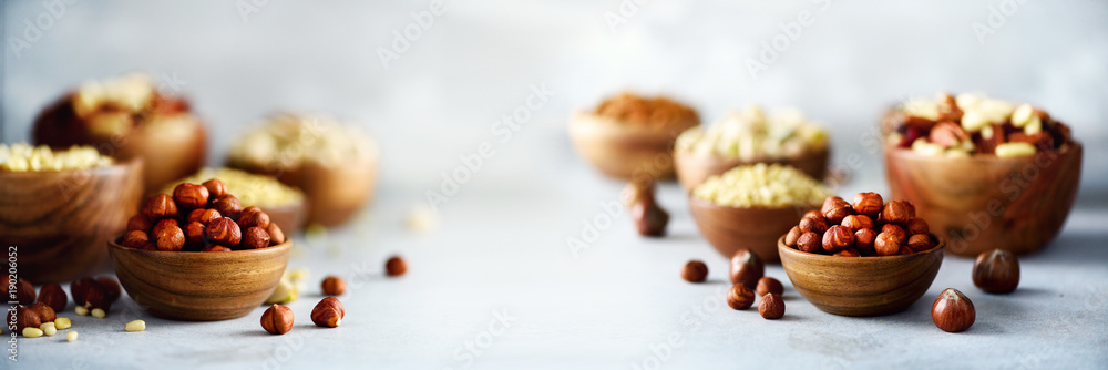 Assortment of nuts in wooden bowls. Cashew, hazelnuts, walnuts, pistachio, pecans, pine nuts, peanut, raisins. Food mix background, top view, copy space, banner. Assortment of nuts in wooden bowls. Cashew, hazelnuts, walnuts, pistachio, pecans, pine nuts, peanut, raisins. Food mix background, top view, copy space, banner.