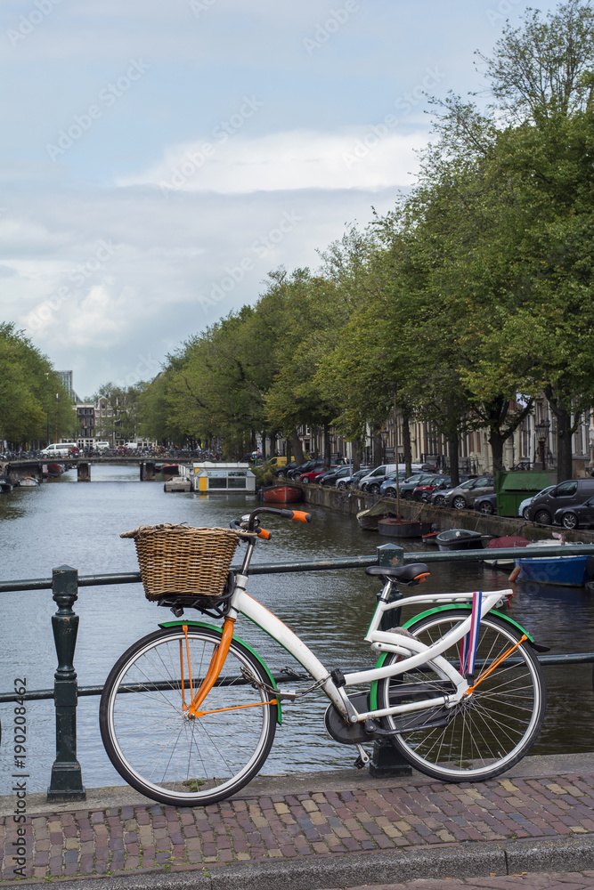 One colourful bike is on the bridge near the canal in Amsterdam in the summer day One colourful bike is on the bridge near the canal in Amsterdam in the summer day