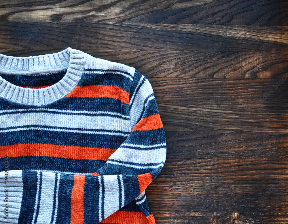 Striped sweater on wooden background. Top view. Striped sweater on wooden background. Top view.