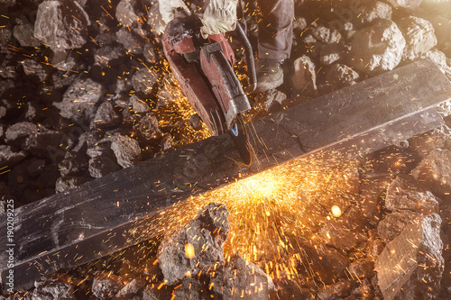 Construction worker cutting an iron beam.