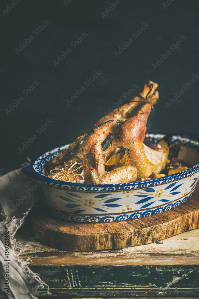 Roasted whole chicken for Christmas eve celebration table on rustic wooden board, black wall background, copy space