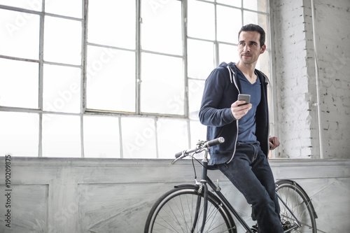 Man sitting on his bicycle, using his smart phone