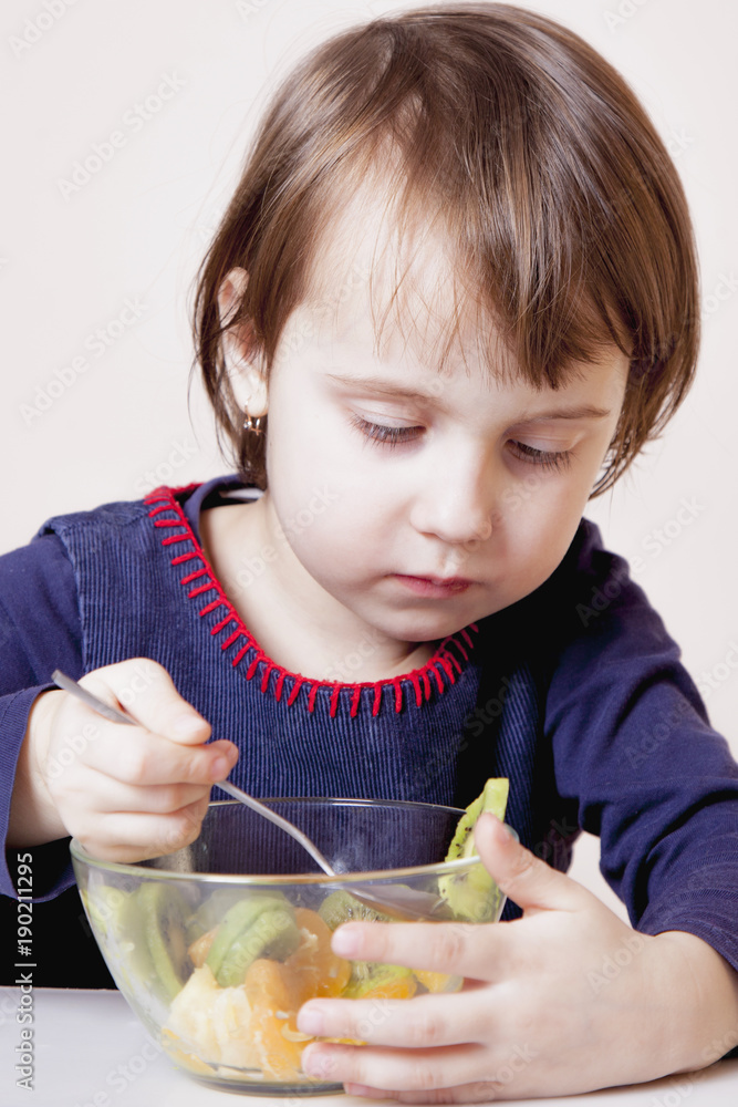 Beautiful child girl eating fruit salad (health, nutritious food concept) Beautiful child girl eating fruit salad (health, nutritious food concept)