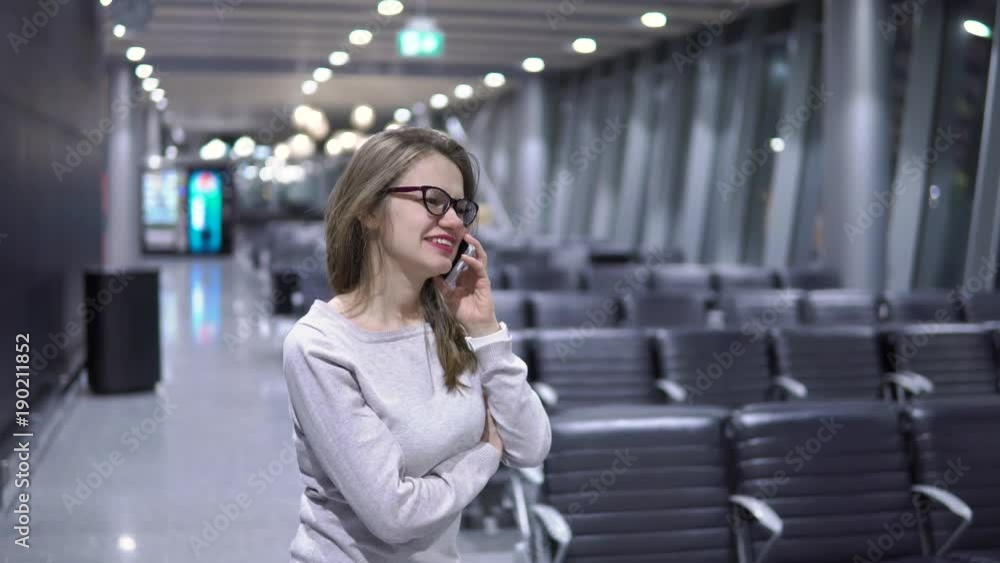 Young, beautiful girl talking on the phone in an empty airport terminal Young, beautiful girl talking on the phone in an empty airport terminal