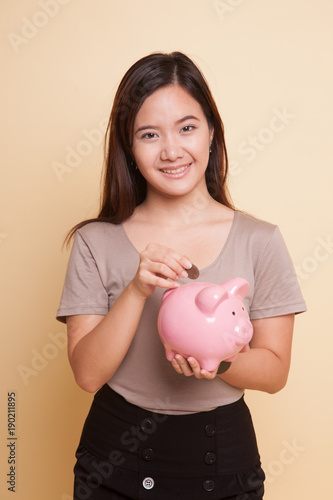 Asian woman with coin and pig coin bank.